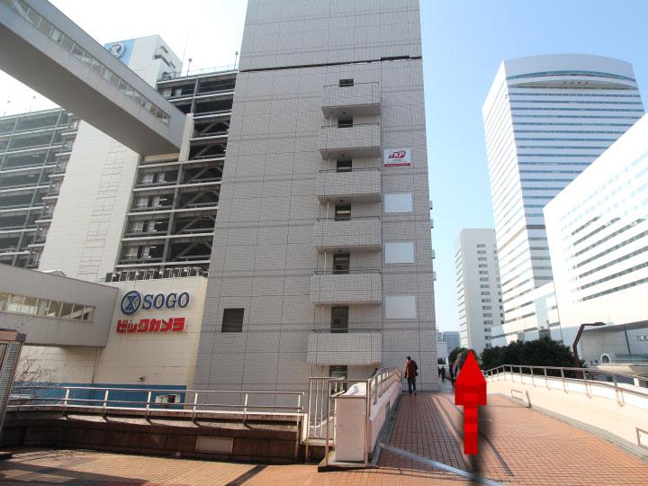 そごうを通り過ぎると前方に見える建物が当施設です。事務所は5Fです。