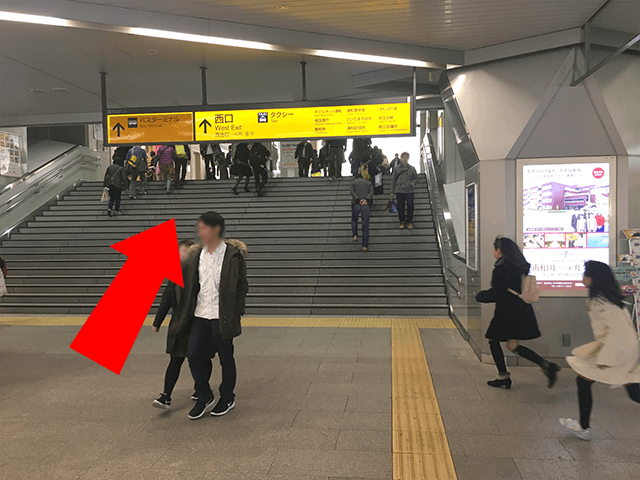 こちらの階段を昇って頂き、西口へ進んでください。